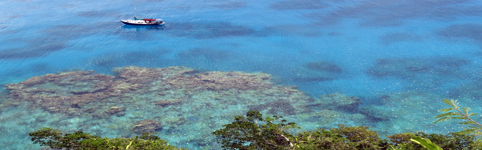 Il s'agit d'une photo aérienne d'un lagon de Nouvelle-Caledonie. On y distingue un petit bateau et on note la transparence des eaux de cette région protégée